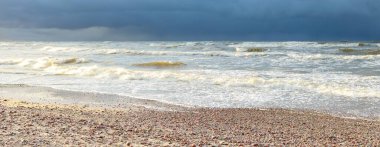 Fırtınadan sonra Baltık kıyıları (kum tepeleri, plaj). Dramatik gökyüzü, parlayan bulutlar. Resimli panoramik manzara. Doğa, çevre, ekoloji, eko-turizm, yürüyüş, keşif kavramları