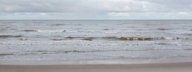 Kumlu bir sahilden (kum tepeleri) Baltık denizinin panoramik görüntüsü. Koyu bulutlu dramatik bir gökyüzü. Dalgalar, su sıçramaları. Idyllic deniz manzarası. Sıcak kış havası, iklim değişikliği, doğa. Danimarka