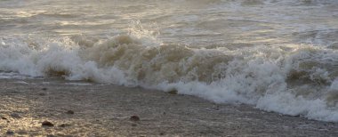 Fırtınadan sonra Baltık kıyıları. Gün batımı, yumuşak güneş ışığı. Su yüzeyi dokusu, çarpan dalgalar, sıçramalar, köpük. Resimli panoramik manzara. Idyllic deniz manzarası. Doğa, çevre, ekoloji temaları