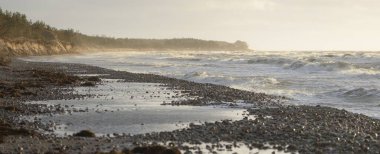 Gün batımında Baltık kıyılarından panoramik manzara. Dramatik bulutlar, parlayan bulutlar, fırtınadan sonra altın güneş ışığı. Doğa, çevre, iklim değişikliği, kararsız hava