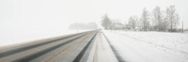 Karla kaplı orman ve kırsal alanda boş otoyol (asfalt yol). Kar fırtınası, kar yağışı. Avrupa. Doğa, Noel tatilleri, uzak yerler, kış lastikleri, tehlikeli sürüş konsepti