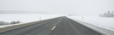 Karla kaplı orman ve kırsal alanda boş otoyol (asfalt yol). Kar fırtınası, kar yağışı. Avrupa. Doğa, Noel tatilleri, uzak yerler, kış lastikleri, tehlikeli sürüş konsepti