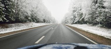 Boş otoyol (asfalt yol) karla kaplı ormanın içinden, kırsal alanda. Arabadan bak. Avrupa. Doğa, Noel tatilleri, uzak yerler, kış lastikleri, tehlikeli sürüş konsepti