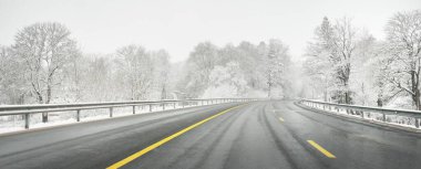 Karla kaplı ormanda boş otoyol (asfalt yol). Kanada mı? Doğa, Noel tatilleri, uzak yerler, kış lastikleri, tehlikeli sürüş konsepti