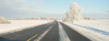 Karla kaplı orman ve kırsal alanda boş otoyol (asfalt yol). Kar sürükleniyor. Avrupa. Doğa, Noel tatilleri, uzak yerler, kış lastikleri, tehlikeli sürüş konsepti