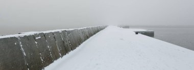 Kumlu sahilden Baltık Denizi 'nin panoramik manzarası. Deniz fenerine dolaş, dalgalar. Yoğun beyaz sis, sis, kar. Dalgalar, su sıçramaları. Deniz Burnu. Tek renkli kış manzarası