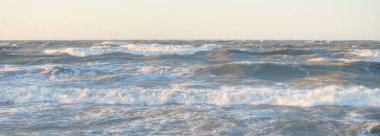 Gün batımında Baltık kıyısı. Yumuşak altın güneş ışığı, parlayan gökyüzü, dalgalar. Idyllic deniz manzarası. Seyahat yerleri, eko turizm, doğa, hava durumu, iklim değişikliği. Resimli panoramik manzara
