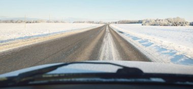 Karla kaplı orman ve kırsal alanda boş otoyol (asfalt yol). Kar sürükleniyor. Avrupa. Doğa, Noel tatilleri, uzak yerler, kış lastikleri, tehlikeli sürüş konsepti