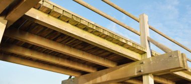 Modern ahşap yürüyüş yolu (bisiklet yolu, tahta yol). Eğlence alanı, orman parkı. Yumuşak güneş ışığı, açık gökyüzü. Baharın başında. Idyllic manzara. Doğa, çevre, ekoloji, eko-turizm, tatiller, hafta sonu