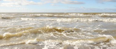 Fırtınadan sonra Baltık Denizi. Dramatik gökyüzü, parlayan bulutlar, yumuşak güneş ışığı. Dalgalar, su sıçratma. Resimli manzara, deniz manzarası, doğa. Panoramik görünüm