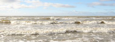 Fırtınadan sonra Baltık Denizi. Dramatik gökyüzü, parlayan bulutlar, yumuşak güneş ışığı. Dalgalar, su sıçratma. Resimli manzara, deniz manzarası, doğa. Panoramik görünüm