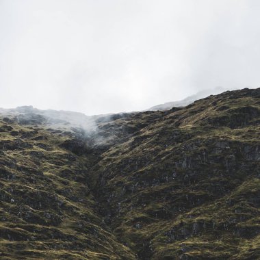 Yeşil kayalık kıyılar ve tepeler akşam sisi bulutları içinde. Lomond Gölü ve Trossachs Ulusal Parkı, Inner Hebrides, İskoçya, İngiltere. Seyahat yerleri, eko turizm, yürüyüş, boş zaman aktiviteleri