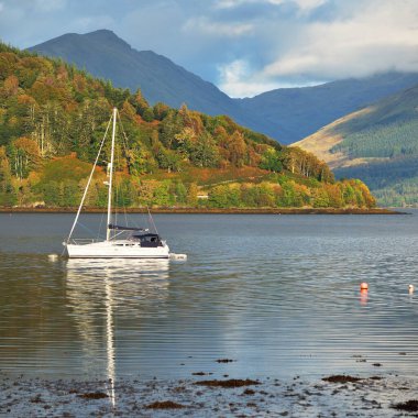 Loch Fyne yakınlarındaki sahil, orman ve tepelerin manzarası. Beyaz yelkenli yatla yakın plan. Inveraray, Inner Hebrides, Argyll ve Bute, İskoçya, İngiltere