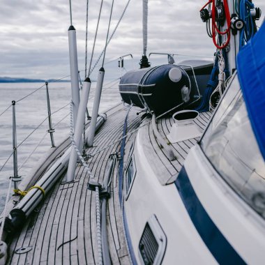 Bulutlu bir günde, Jura adasının kayalık kıyılarında seyir halindeki ahşap meşe güvertesiyle donatılmış modern bir yat. Inner Hebrides, İskoçya, İngiltere. Spor, eğlence, gezi, seyahat yerleri.