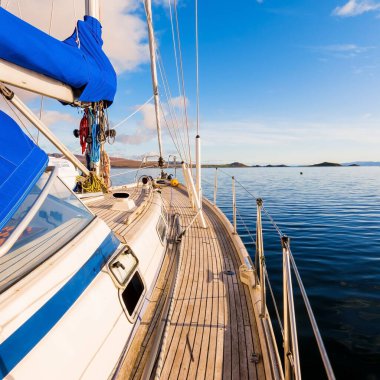 Günbatımında Jura adasının kayalık kıyılarında seyir halindeki ahşap meşe güvertesiyle donatılmış modern bir yat. Inner Hebrides, İskoçya, İngiltere. Spor, eğlence, gezi, seyahat yerleri.