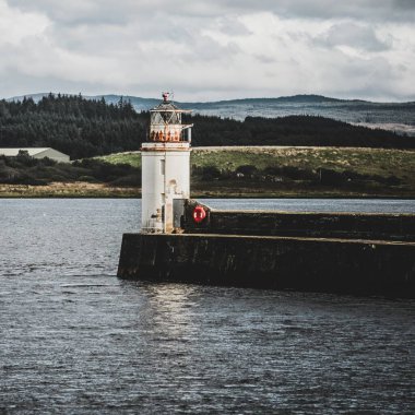 Eski deniz fenerine doğru boş bir gezinti, yakın plan. Arka planda kayalık kıyılar var. Dramatik bulut manzarası. Ardrishaig, Crinan Kanalı, İskoçya, İngiltere. Seyahat yerleri, gezi teması