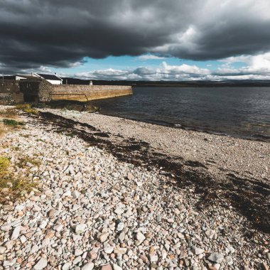 Eski deniz fenerine boş bir gezinti alanı, çakıllı plaj yakınlaşması. Dramatik bulut manzarası. Ardrishaig, Crinan Kanalı, İskoçya, İngiltere. Seyahat yerleri, gezi teması
