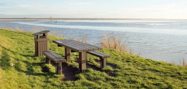Modern dinlenme alanı, orman parkı, göl. Tahta banklar, masalar. Kamp alanı. Yumuşak güneş ışığı, açık gökyüzü. Baharın başında. Idyllic manzara. Doğa, çevre, ekoloji, eko-turizm, tatiller, hafta sonu