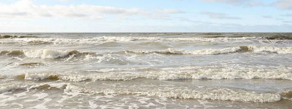 Fırtınadan sonra Baltık Denizi. Dramatik gökyüzü, parlayan bulutlar, yumuşak güneş ışığı. Dalgalar, su sıçratma. Resimli manzara, deniz manzarası, doğa. Panoramik görünüm