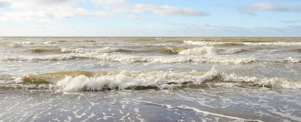 Fırtınadan sonra Baltık Denizi. Dramatik gökyüzü, parlayan bulutlar, yumuşak güneş ışığı. Dalgalar, su sıçratma. Resimli manzara, deniz manzarası, doğa. Panoramik görünüm