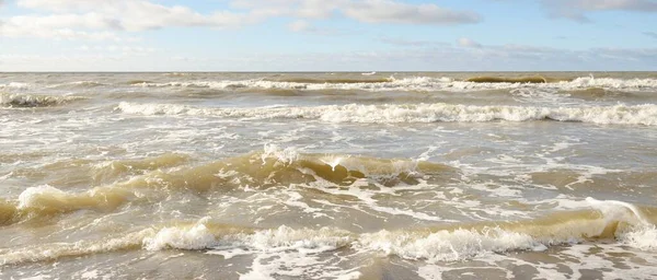 Fırtınadan sonra Baltık Denizi. Dramatik gökyüzü, parlayan bulutlar, yumuşak güneş ışığı. Dalgalar, su sıçratma. Resimli manzara, deniz manzarası, doğa. Panoramik görünüm