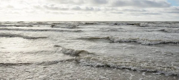 Fırtınadan sonra Baltık Denizi. Dramatik gökyüzü, parlayan bulutlar, yumuşak güneş ışığı. Dalgalar, su sıçratma. Resimli manzara, deniz manzarası, doğa. Panoramik görünüm