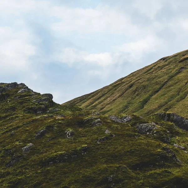 Yeşil kayalık kıyılar ve dramatik mavi gökyüzünün altındaki tepeler. Lomond Gölü ve Trossachs Ulusal Parkı, Inner Hebrides, İskoçya, İngiltere. Seyahat yerleri, eko turizm, yürüyüş, boş zaman aktiviteleri