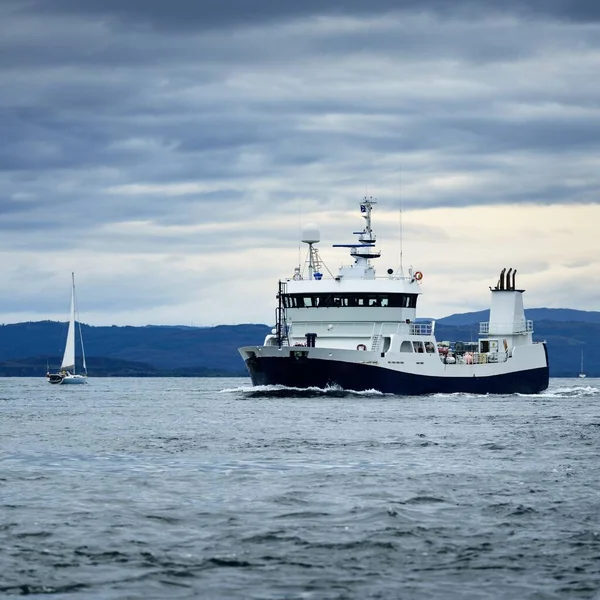 Bulutlu bir günde, iç Hebrides adalarındaki kayalıkların, dağların ve vadilerin panoramik manzarası. İskoçya, İngiltere. Beyaz yelkenli tekne ve balıkçı teknesi.