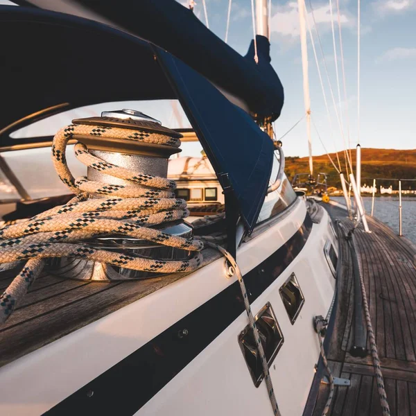 Sloop rigged modern yacht with wooden teak deck sailing near the rocky shore of Jura island at sunset, close-up. Inner Hebrides, Scotland, UK. Sport, recreation, cruise, travel destinations