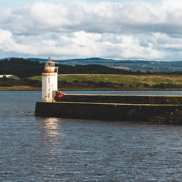 Eski deniz fenerine doğru boş bir gezinti, yakın plan. Arka planda kayalık kıyılar var. Dramatik bulut manzarası. Ardrishaig, Crinan Kanalı, İskoçya, İngiltere. Seyahat yerleri, gezi teması