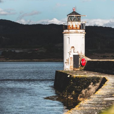 Eski deniz fenerine doğru boş bir gezinti, yakın plan. Arka planda kayalık kıyılar var. Dramatik bulut manzarası. Ardrishaig, Crinan Kanalı, İskoçya, İngiltere. Seyahat yerleri, gezi teması
