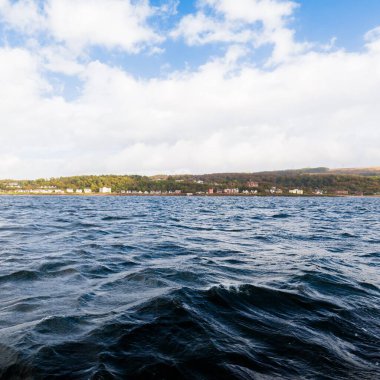 Ormanlık, tepeler ve dağlar Firth of Clyde nehrinin yanında, yelkenli bir teknenin manzarası. Fırtınadan sonra dramatik bir gökyüzü. İskoçya, İngiltere. Seyahat yerleri, eko turizm, saf doğa. Atmosferik manzara
