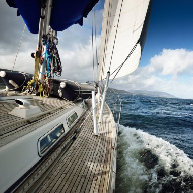 Bulutlu bir günde ahşap meşe güverteli, yelkenli, modern bir yat. Direğe ve yelkenlere bir manzara. Gare Loch, Clyde Firth, İskoçya, İngiltere