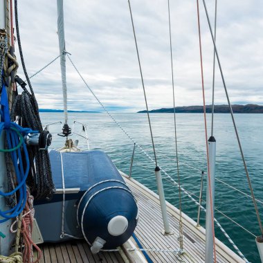 Bulutlu bir günde, Jura adasının kayalık kıyılarında seyir halindeki ahşap meşe güvertesiyle donatılmış modern bir yat. Inner Hebrides, İskoçya, İngiltere. Spor, eğlence, gezi, seyahat yerleri.