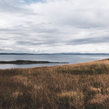 Jura adasının kıyıları, dağları ve vadilerinin panoramik hava manzarası. Bulutlu mavi gökyüzü. Fırtınalı hava. Paps of Jura, Inner Hebrides, İskoçya, İngiltere. Seyahat yerleri, turizm, ulusal simgeler