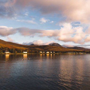 Jura Papaları 'nın yakınlarındaki vadiyi renkli fırtınalı günbatımı altında panoramik açıdan görmek. Geleneksel kır evleri. Dramatik bulut manzarası. Craighouse, Jura Adası, Inner Hebrides, İskoçya, İngiltere