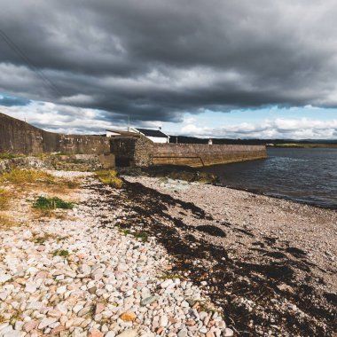 Eski deniz fenerine boş bir gezinti alanı, çakıllı plaj yakınlaşması. Dramatik bulut manzarası. Ardrishaig, Crinan Kanalı, İskoçya, İngiltere. Seyahat yerleri, gezi teması