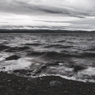 Kayalık kıyılar, kayalıklar, dağ tepeleri, Crinan ormanları ve tepeleri, dalgalar yakın. Ardrishaig, Argyll ve Bute, İskoçya, İngiltere. Panoramik manzara. Dramatik bir gökyüzü. Seyahat yerleri, turizm