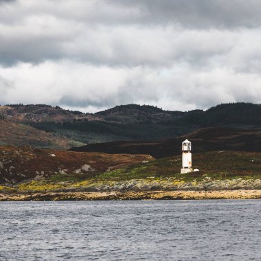 Dramatik gökyüzü altında Tarbert 'in kayalık kıyılarının panoramik manzarası. Arka planda deniz feneri, İskoçya, İngiltere. Seyahat yerleri, ulusal dönüm noktası, eğlence, eko turizm, tatiller