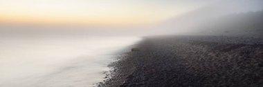Baltık deniz kıyısının sisli manzarası nefes kesici panoramik. Parlak gökyüzü, gece yarısı güneşi, alacakaranlık. Resimli bir manzara var. Rüya gibi bir manzara. Saf doğa, çevre, ekoloji, turizm