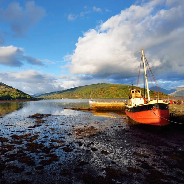 Loch Fyne yakınlarındaki sahil, orman ve tepelerin manzarası. Kırmızı balıkçı teknesi. Inveraray, Inner Hebrides, Argyll ve Bute, İskoçya, İngiltere