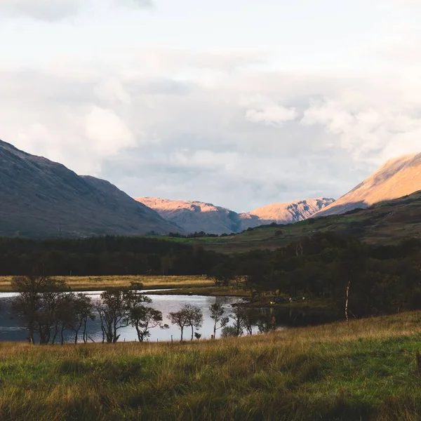 Majestic forest hills and mountain peaks near the shore of Loch Fyne. Dramatic sunset sky. Inveraray, Argyll and Bute, Scotland, UK. Travel destinations, national landmarks, eco tourism