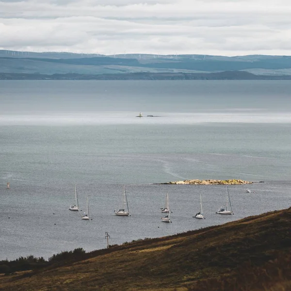 Panoramic aerial view of the shores, mountains and valleys of Jura island. Yachts anchored on mooring. near the Paps of Jura, Inner Hebrides, Scotland, UK. Travel destinations, tourism, sailing