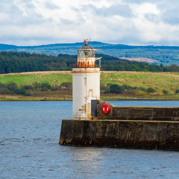 Eski deniz fenerine doğru boş bir gezinti, yakın plan. Arka planda kayalık kıyılar var. Dramatik bulut manzarası. Ardrishaig, Crinan Kanalı, İskoçya, İngiltere. Seyahat yerleri, gezi teması