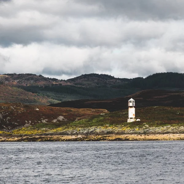 Panoramic view of the rocky shores of Tarbert under dramatic sky. Lighthouse in the background, Scotland, UK. Travel destinations, national landmark, recreation, eco tourism, vacations