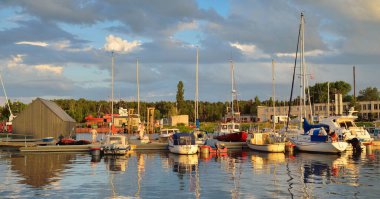 Şık ve modern yelkenliler ve kesiciler gün batımında yat limanında bir rıhtıma demirlediler. Tatiller, ulaşım, spor, eğlence, turizm, seyahat, liman