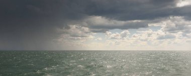 Baltık Denizi dramatik bulutların altında. Fırtına var. Mavi gökyüzü. Sahilden panoramik hava manzarası. Deniz Burnu. Kasırga, fırtına, sert hava, meteoroloji, iklim değişikliği, doğal fenomen