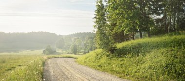 Gün doğarken yeşil tarlalardan ve ormandan arabayla geçmek. Idyllic kırsal alanı, konsept manzarası. Doğa, uzak yerler, lojistik, yaz tatili, yol gezisi, eko-turizm, özgürlük