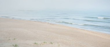 Güneşin doğuşunda sisli bir havada Baltık Denizi manzarası. Kumsal, kum tepeleri. Yumuşak güneş ışığı. Idyllic yaz deniz manzarası. Doğa, çevre, tatiller, eko-turizm, yürüyüş ve keşif kavramları