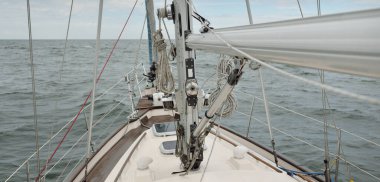 Fırtınada açık denizde yelken açan eski klasik bir yat. Tahta meşe güvertesi. Ketçap yelkenli. Dalgalar, su sıçramaları. Gezi, tatil, yelkenli yarışı, spor, boş zaman aktivitesi.